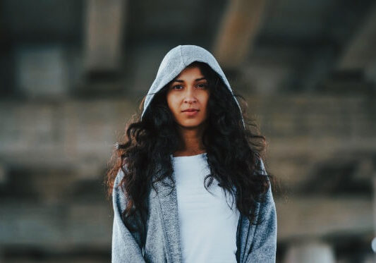portrait-of-young-woman-standing-in-hoodie